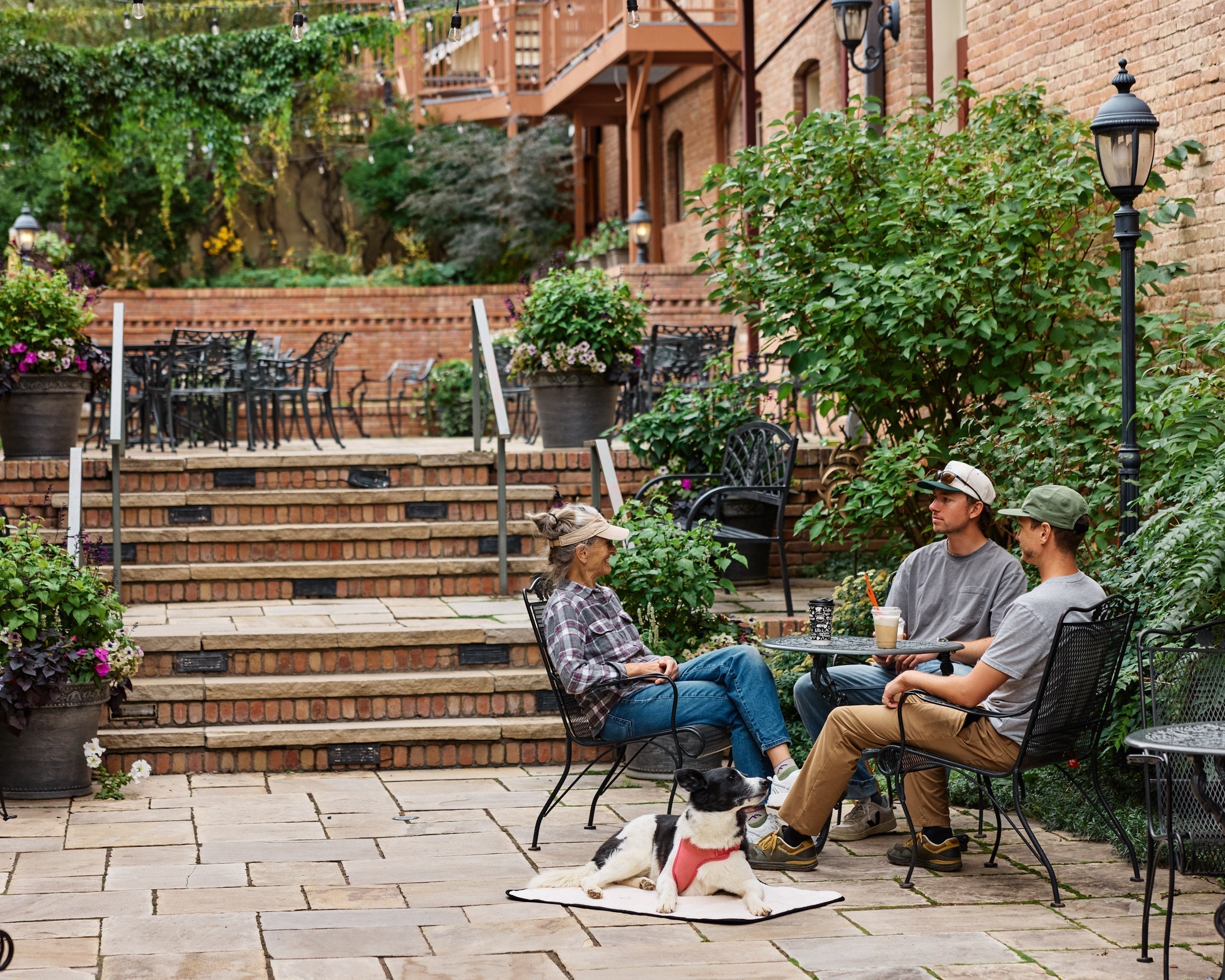 a group of people sitting at a cafe with a dog laying on a My Place portable dog bed